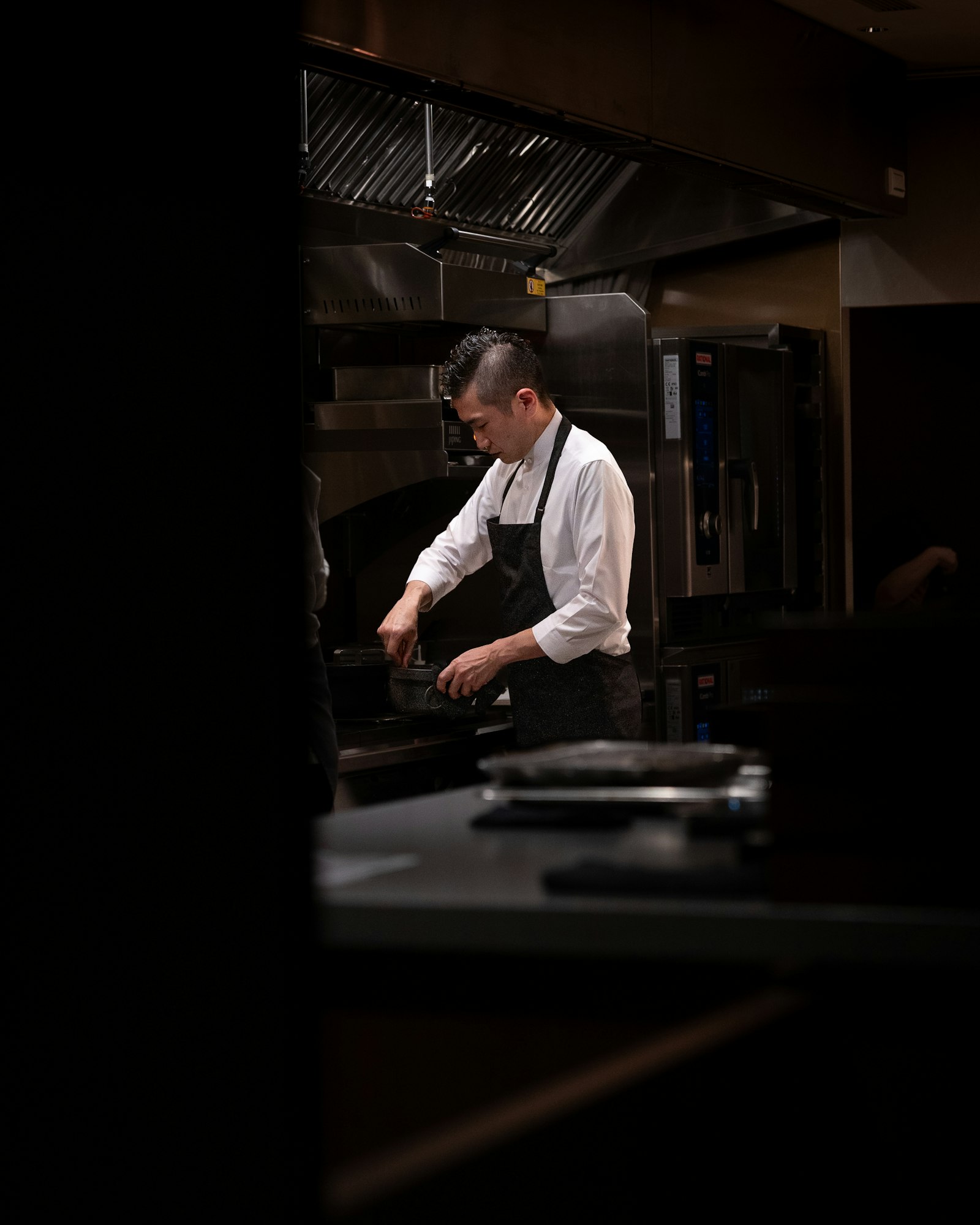 A chef cooking on the line in a commercial restaurant kitchen during service